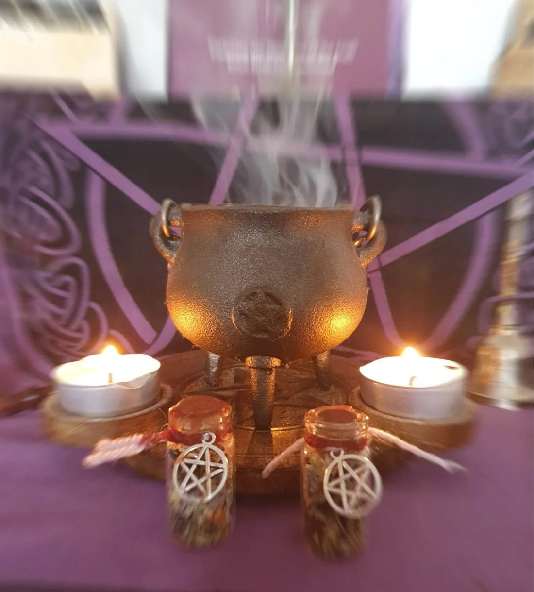 Cauldron with burning sage smoke and lit candles creating sacred space for home cleansing ritual - traditional smudging setup with pentagram charms for spiritual protection