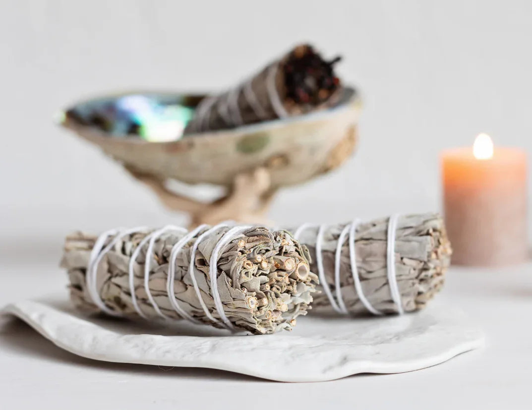 California White Sage smudge sticks with abalone shell and lit candle - traditional sacred cleansing herbs for spiritual purification and negative energy removal